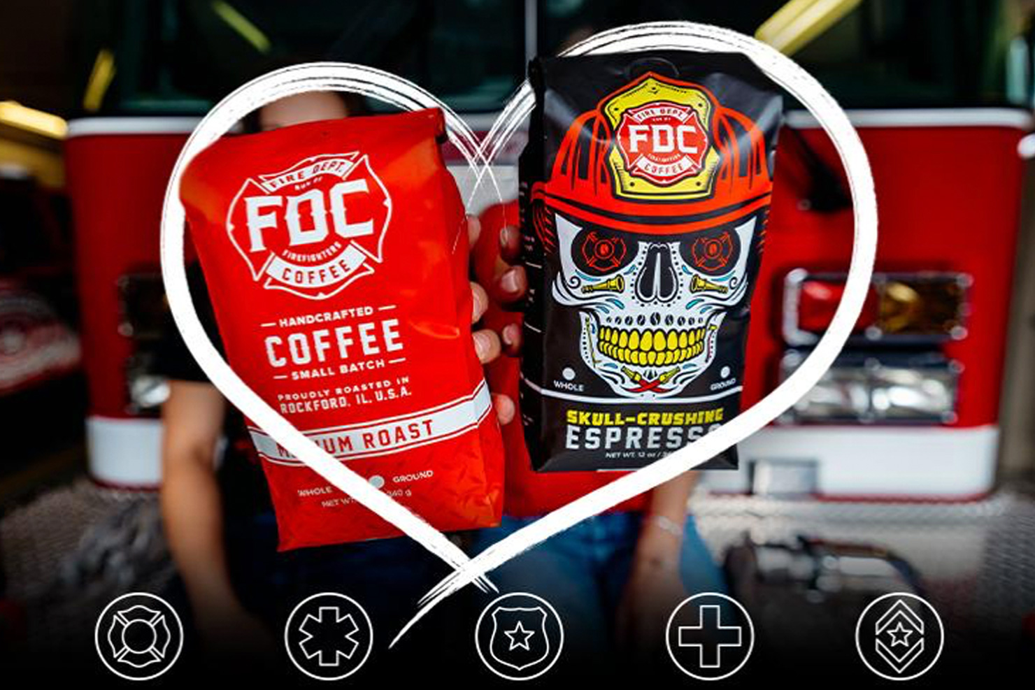 Two Fire Department Coffee bags being held out toward the camera. One bag is Medium Roast Coffee and the other is Shellback Espresso Coffee. The coffee bags are wrapped with a superimposed image of a heart and below are icons for Firefighter, Paramedics/EMS, Police, Nurses and Military members. The background is the setting of a fire station and showing the front end of a red firetruck.