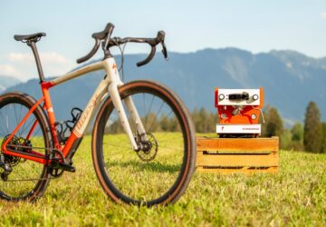 bicycle on grass with espresso machine in background mountains and sky behind it