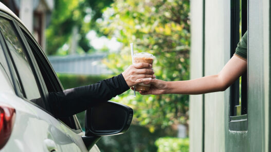 young man receiving coffee at drive thru counter., drive thru and take away for protect covid19.